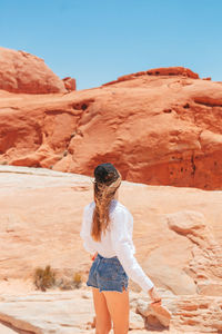 Rear view of woman standing at rock formations