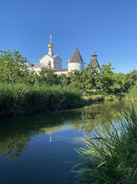 Buildings by lake against clear sky