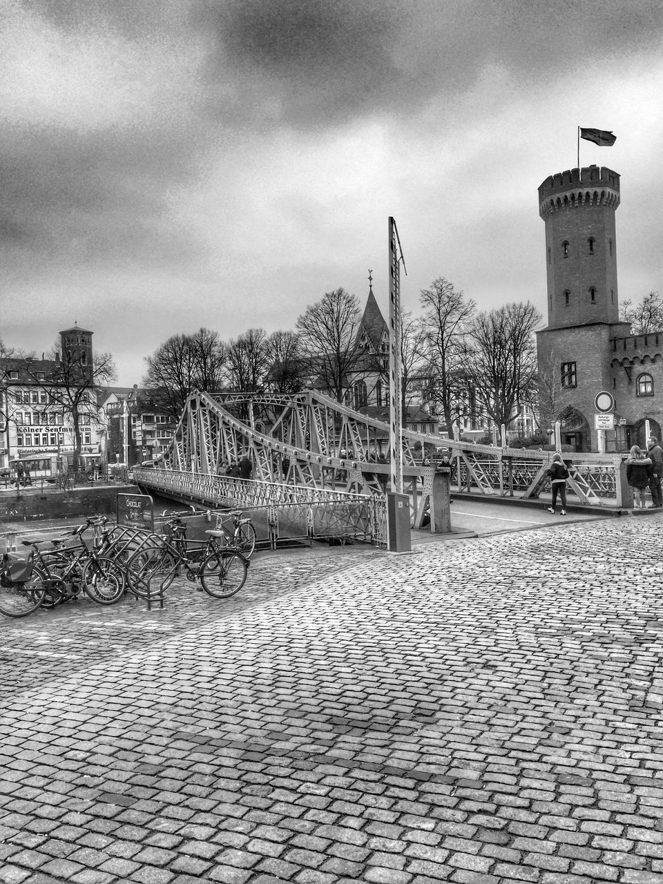 architecture, built structure, building exterior, sky, cloud - sky, tree, street light, railing, cloudy, cloud, city, day, gate, outdoors, incidental people, cobblestone, building, no people, footpath, walkway