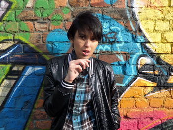 Portrait of serious woman against graffiti wall
