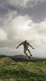 Low angle view of person jumping on field against sky