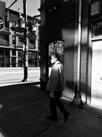 Rear view of man walking on street in city