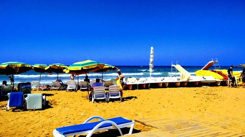 Deck chairs on beach against clear blue sky