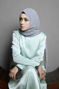 Young woman sitting against wall