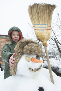 Smiling boy making snowman in yard during winter