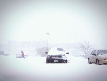 Snow covered car on street against sky