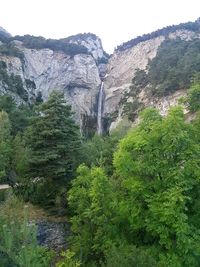 Scenic view of waterfall in forest against sky