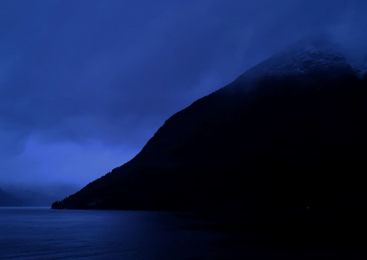 SCENIC VIEW OF SEA BY SILHOUETTE MOUNTAIN AGAINST SKY AT DUSK