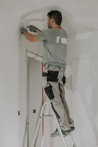 A young builder is plastering a doorway.