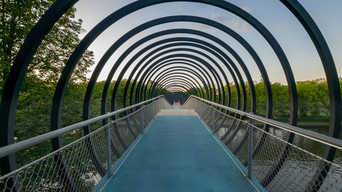 Rear view of person on footbridge against sky