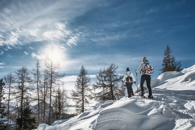 Couple of women friends on snow trip with snowshoeing on a sunny day