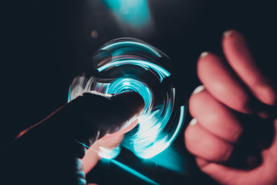 Close-up of hand holding illuminated fidget spinner