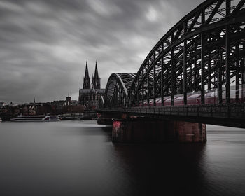 Bridge over river in city against sky