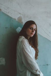 Young woman standing against wall