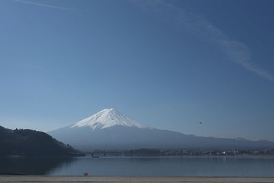 Scenic view of lake and snowcapped mountains against blue sky