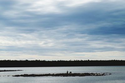 View of calm lake against cloudy sky