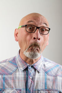 Close-up portrait of man in eyeglasses against gray background