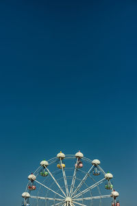 Low angle view of ferris wheel against clear blue sky