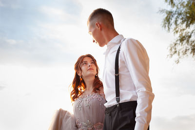 Young couple standing against sky