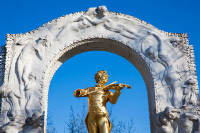 Low angle view of angel statue against clear blue sky