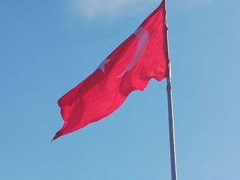 Low angle view of flag against blue sky