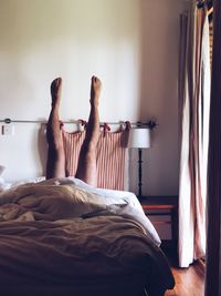 Low section of man relaxing on bed at home