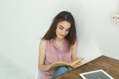 Young woman looking away while sitting on table