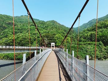 Footbridge amidst trees against mountains