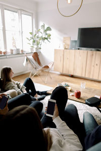 Teenagers using mobile phones while relaxing at home