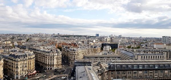 High angle view of city buildings against cloudy sky