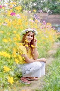 Portrait of smiling young woman sitting by plants