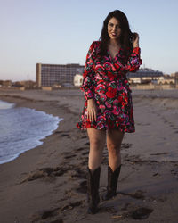 Full length of woman standing at beach against sky