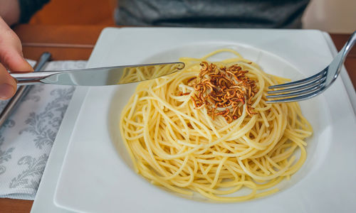 Cropped image of man having noodles and worms in restaurant