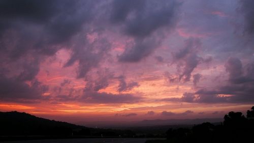 Scenic view of mountains against cloudy sky at sunset