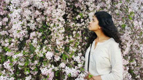 Woman looking at white flowers at park