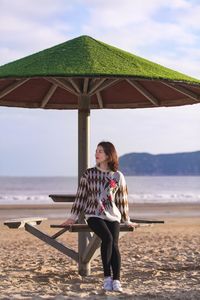 Full length of woman standing on beach against sky