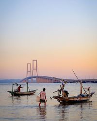People on sea against sky during sunset