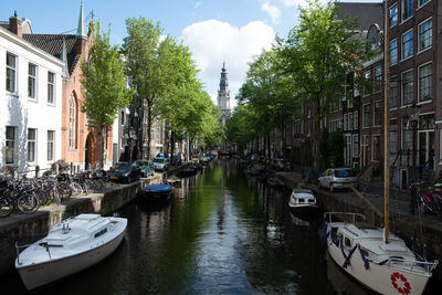 Boats moored in canal amidst buildings in city