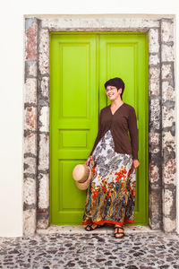 Portrait of smiling woman standing against door