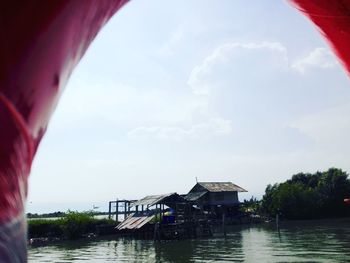 Houses by river against sky