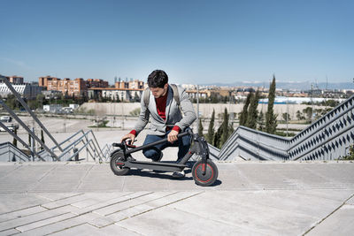 Man riding bicycle on river in city against clear sky