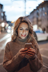 Young woman using mobile phone in city