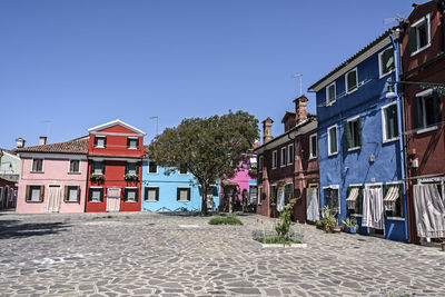 Houses by street in town against clear blue sky