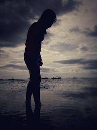 Silhouette of man standing by sea against sky