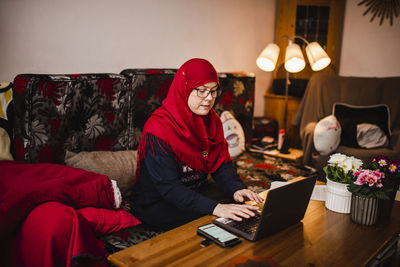 Midsection of man using mobile phone while sitting on table