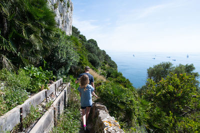 Rear view of women on plants by sea against sky