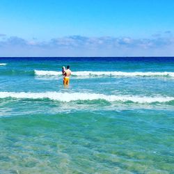 Woman in sea against sky