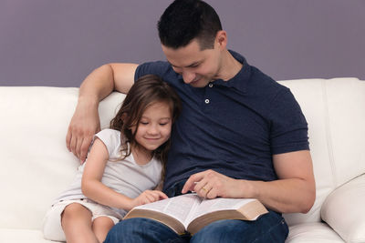 Father and daughter sitting on sofa