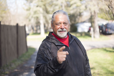 Portrait of mature man gesturing standing at park