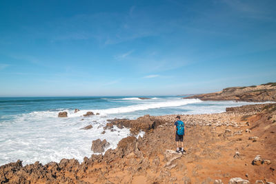 Rear view of woman walking at beach against sky